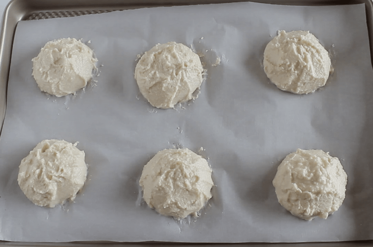 Paleo biscuit dough in 6 heaps on a baking sheet lined with white parchment paper