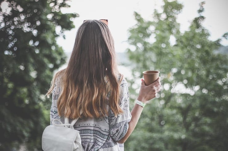 Back view of a woman with a mug looking at trees