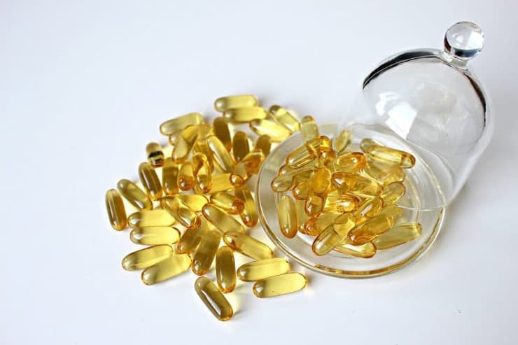 Yellow gel capsules on a clear plate spilling onto a white table