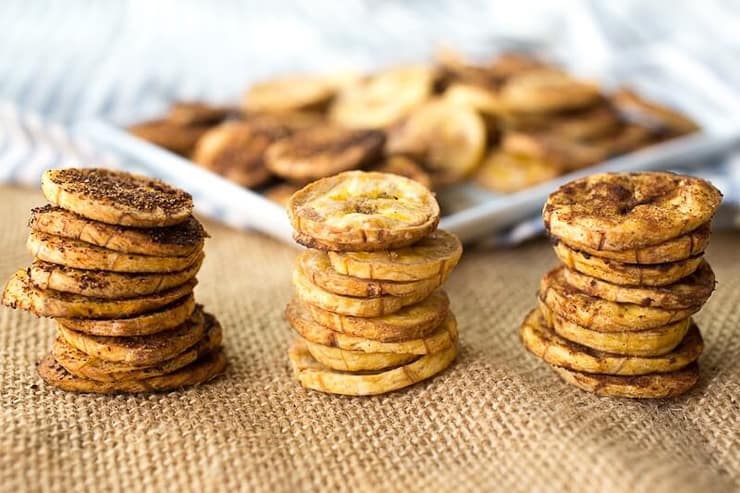 Three stacks of plantain chips with a plateful in the background