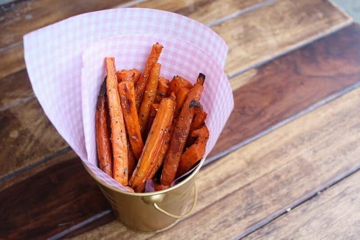 A pot of carrot fries sitting on a wooden surface