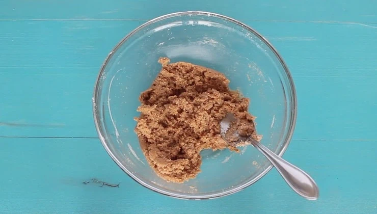 overhead view of dough mixture in clear bowl on blue wooden table