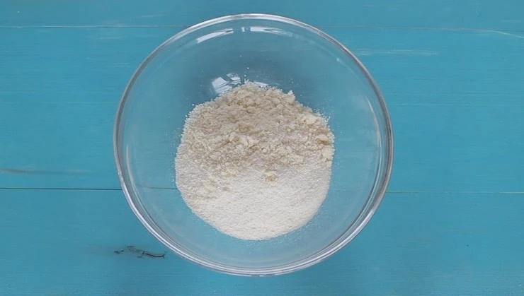 overhead view of dry ingredients in clear bowl on blue wooden table