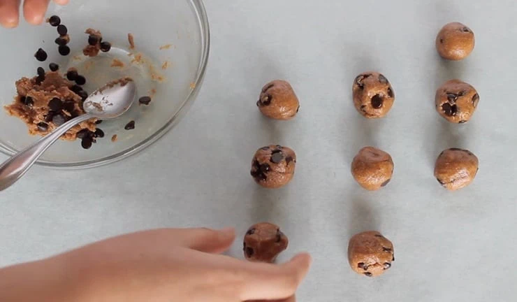 overhead view of dough being rolled into balls on parchment paper