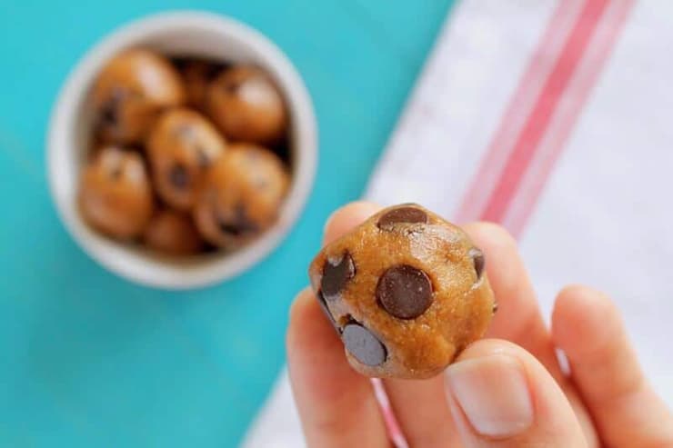 A hand holding a chocolate chip energy balls with more in the background