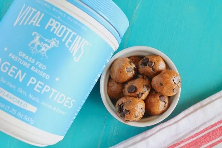 An overhead shot of energy balls in a ramekin and a tub of collagen peptides at the side