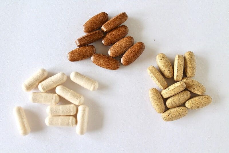 three groups of different colored vitamins on a white table