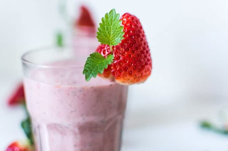 A strawberry smoothie garnish with a strawberry at the side