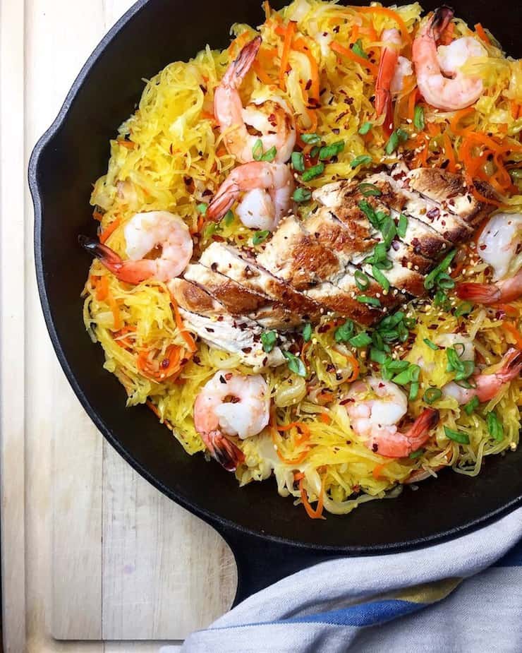 Cast iron skillet filled with yellow spaghetti squash meat and shrimp