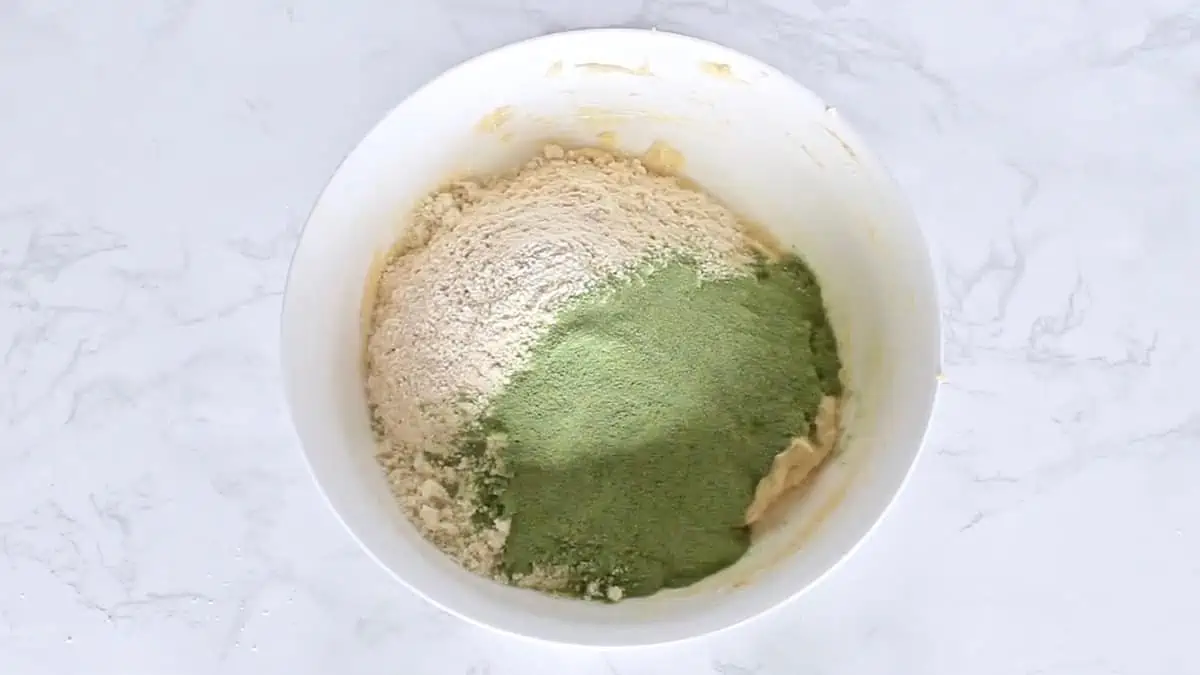Flours and green matcha powder in a white mixing bowl