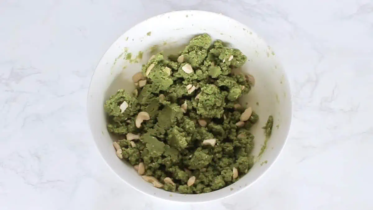 Green matcha cookie dough with cashews mixed in in a white bowl