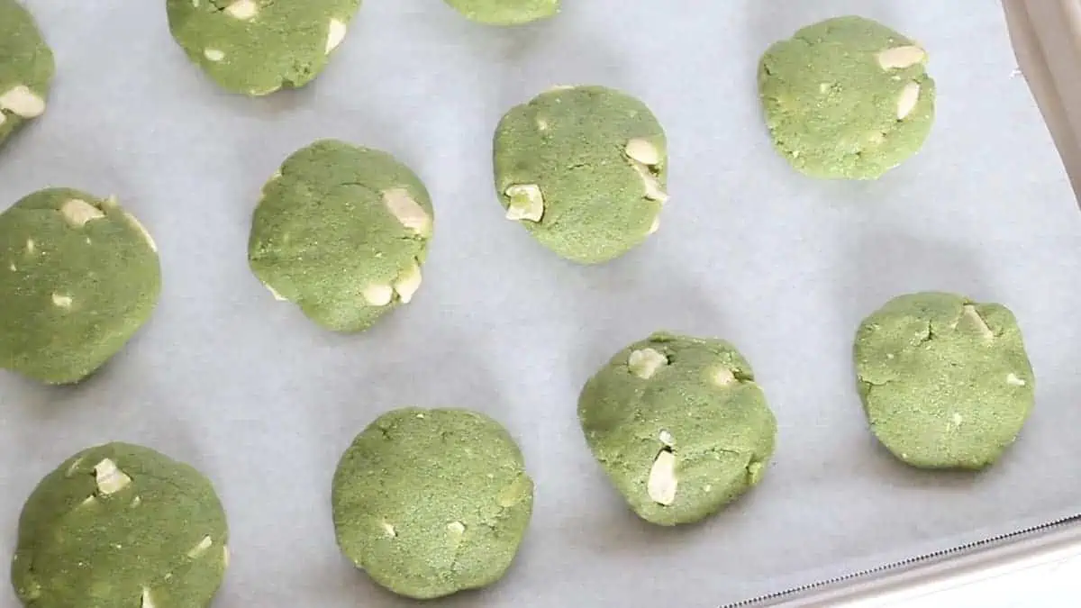 Uncooked matcha cookies on a baking sheet lined with parchment paper