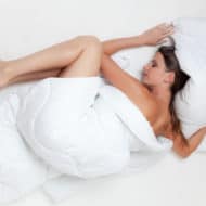 A woman sleeping white white covers and pillows