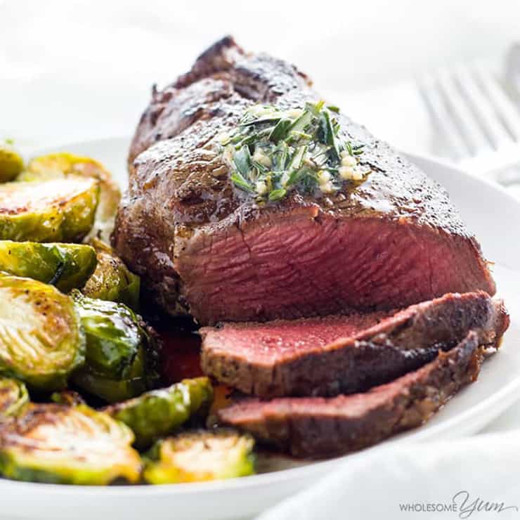 Filet mignon beef on a plate cut into slices with vegetables at the side