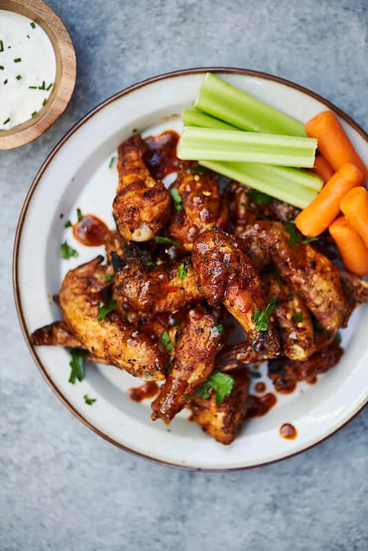 A plate of cooked chicken wings with celery and carrot sticks