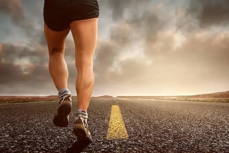 close up of man's legs running on an asphalt road