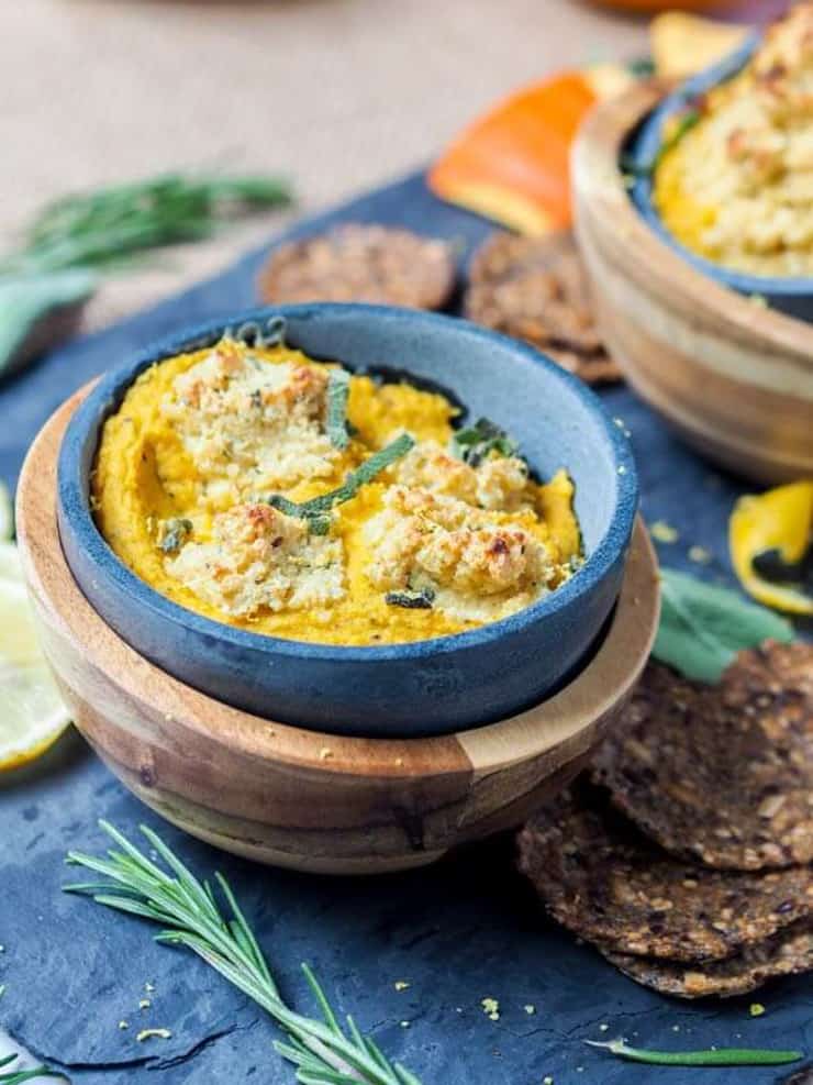 A blue bowl of pumpkin dip topped with herbs