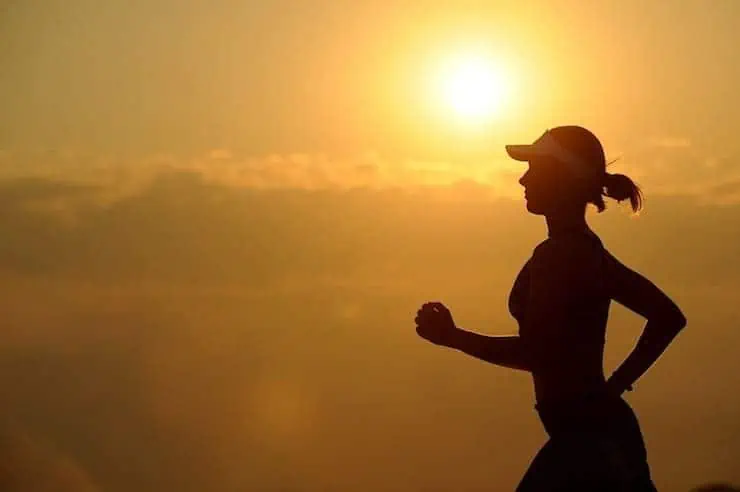 Silhouette of woman running with sunset in background 