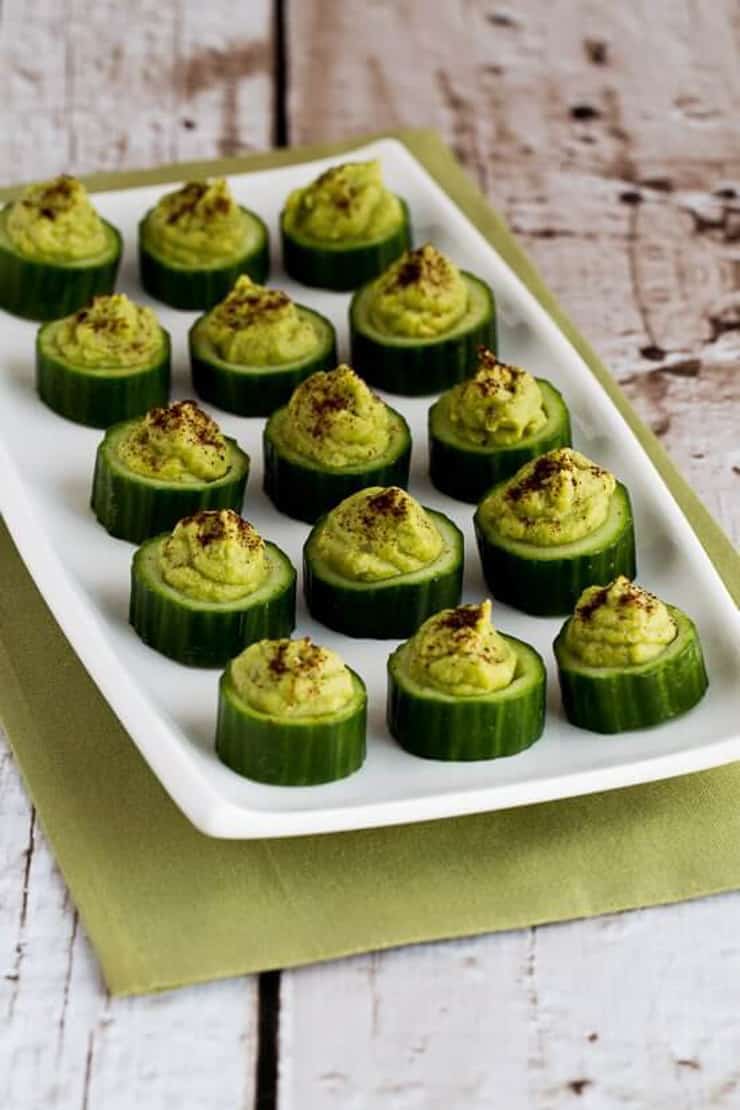 Cucumber bites stuffed with guacamole on a white plate