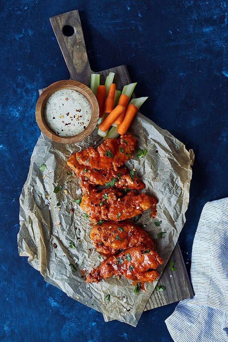 Chicken fingers on brown paper with a dipping sauce