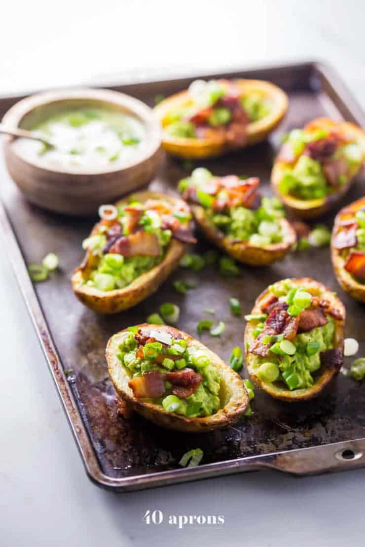 healthy potato skins on a baking tray with toppings an a dip