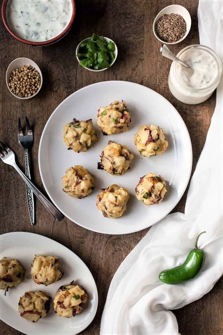 Samosa bites on a white plate with two forks