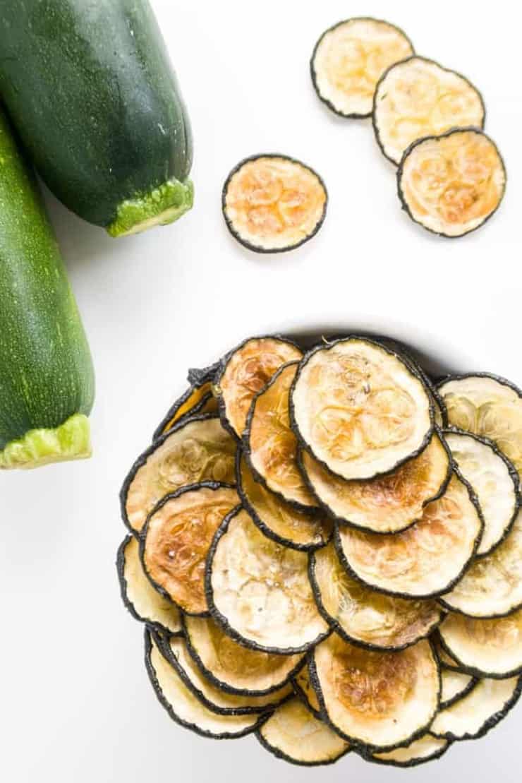 Zucchini chips in a large bowl with some spilling out over the edge