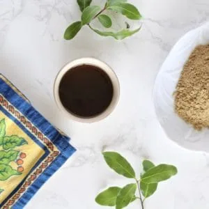 Overhead view of cup of essiac tea with powder and floral napkin beside it