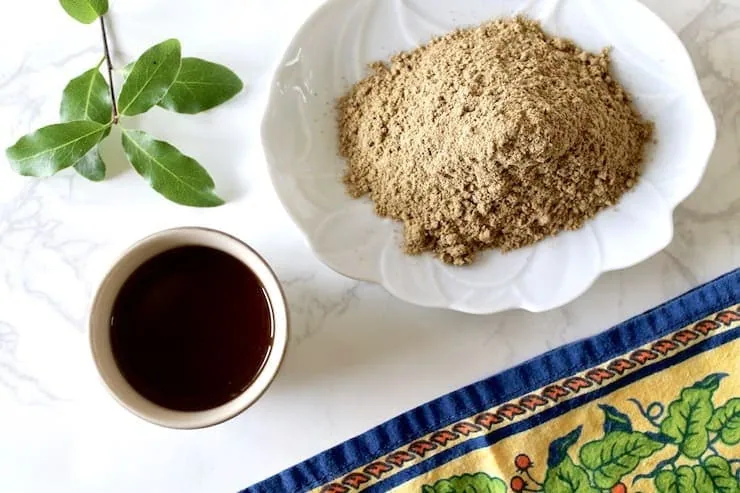 Overhead view of cup of essiac tea with powder and floral napkin beside it