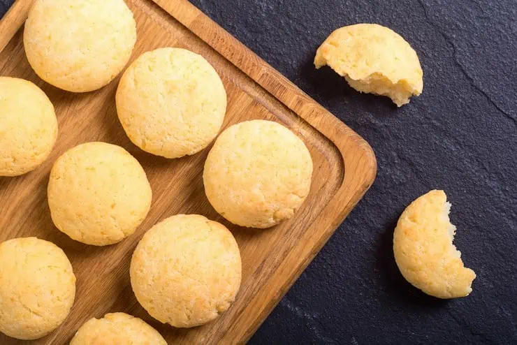 grain free garlic bread rolls on a wooden cutting board on top of a black slate surface with one ripped roll on the black slate