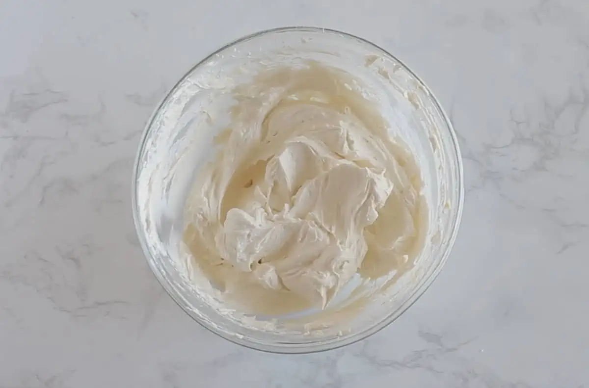 Bowl of white vanilla keto buttercream frosting in clear bowl