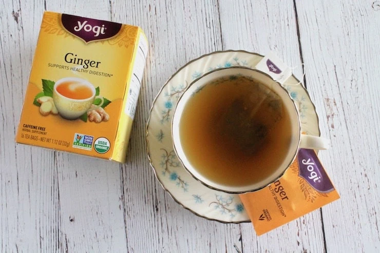 Cup of tea on a saucer with box of ginger tea next to it