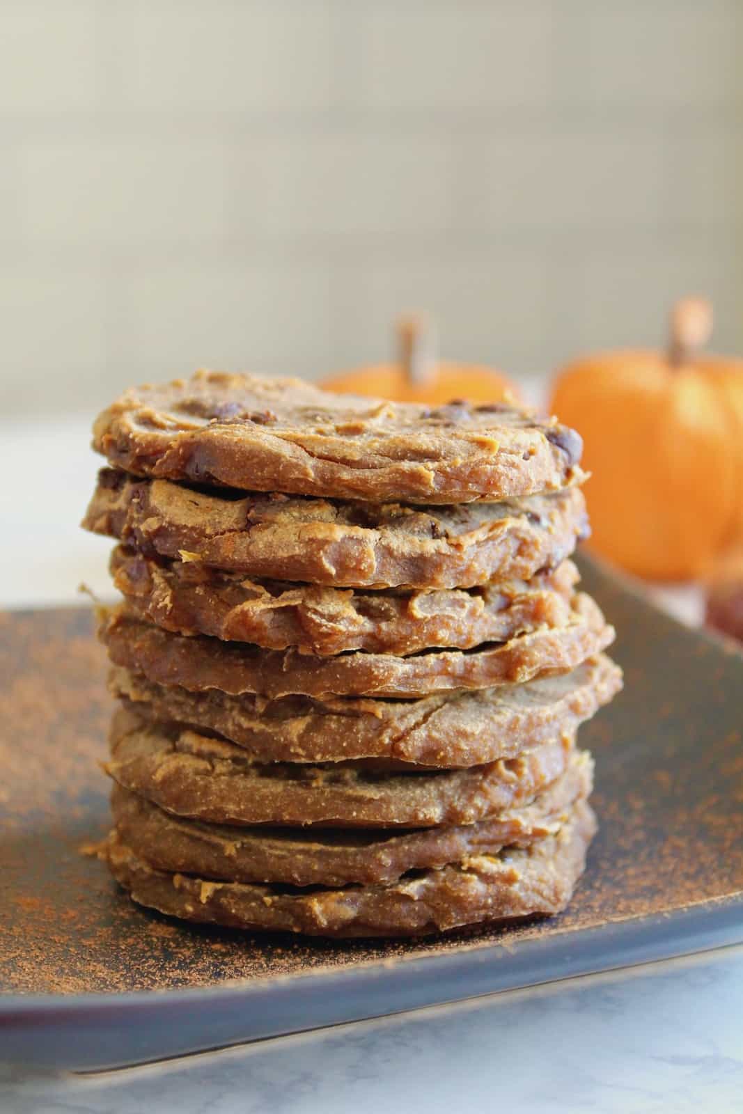 Close up of Stack of banana pumpkin cookies on black plate with pumpkins and dates in background