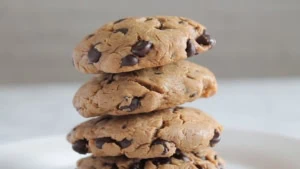 close up of four keto chocolate chip cookies stacked on a white plate with white background