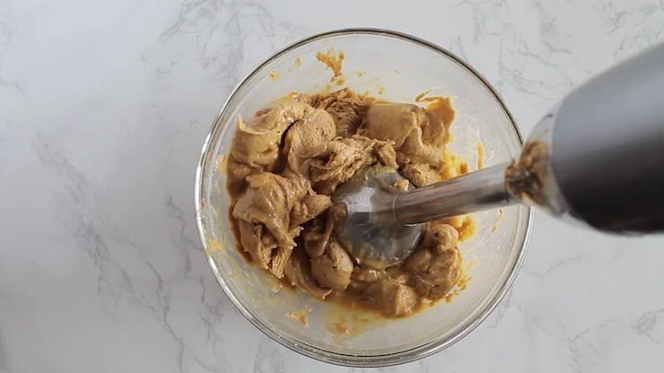 clear bowl of keto cookie dough without the chocolate chips mixed by stick blender