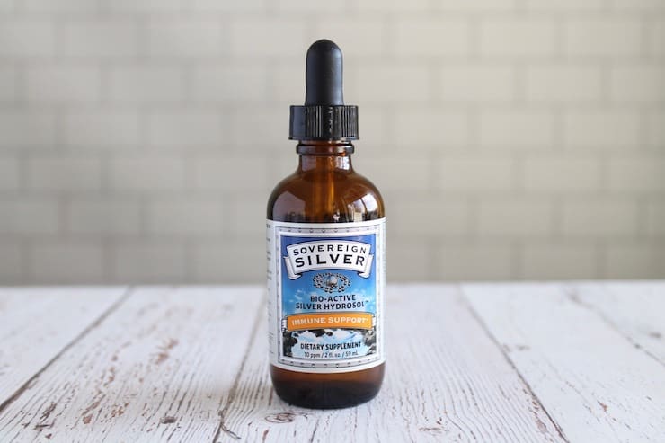 Amber dropper bottle of colloidal silver on a white wooden table