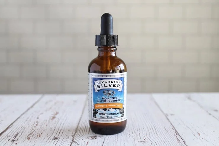 Amber dropper bottle of colloidal silver on a white wooden table