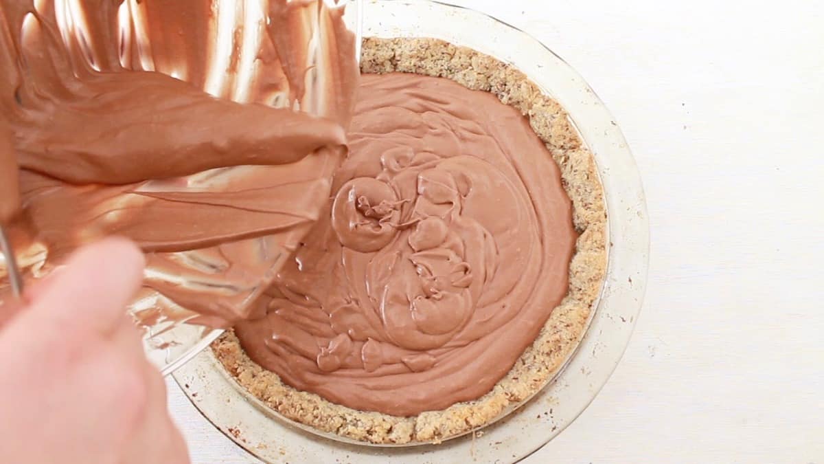 Overhead view of chocolate cream pie filling being poured into the crust