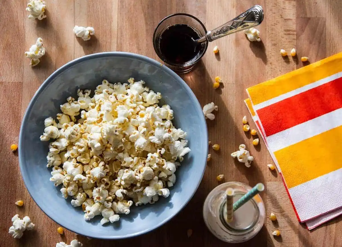 Overhead view of popcorn in a large grey bowl with drinks beside it