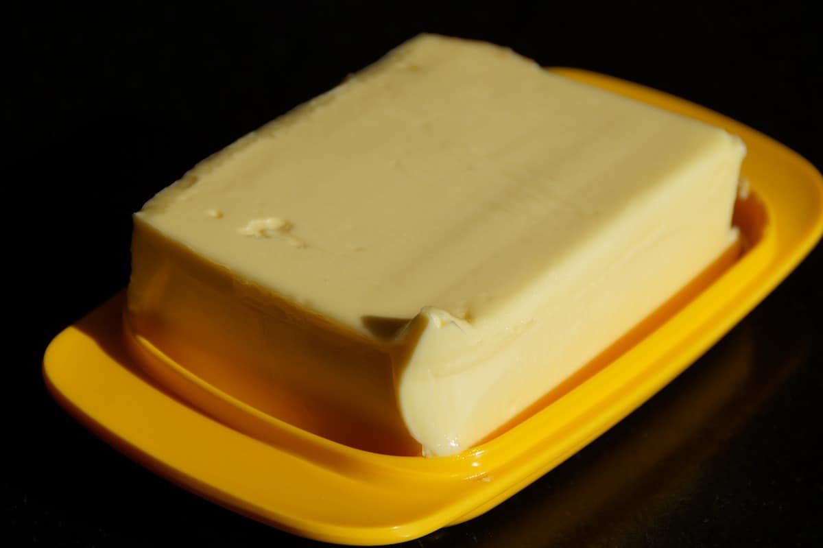 Slab of butter on a yellow plastic holder on a black surface