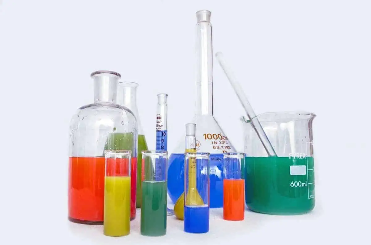 Different sized beakers with various colored liquids in them on a white table