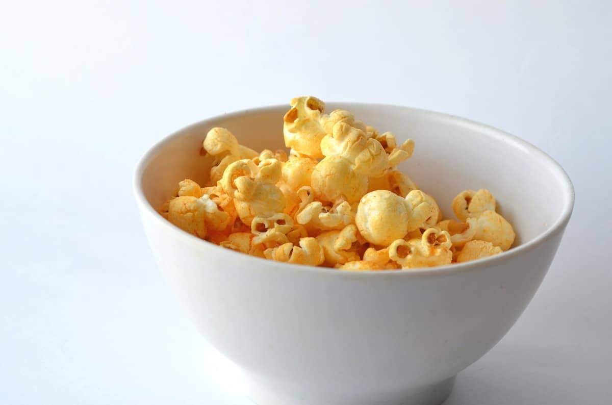 Popcorn in a white bowl on a white surface