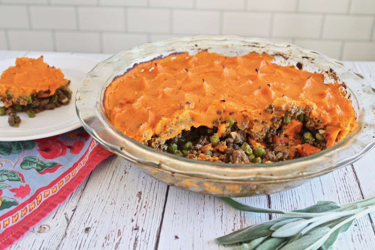sweet potato shepherd's pie with pieces taken out of it and a slice on a separate white plate behind it