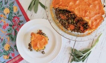 overhead view of sweet potato shepherd's pie with pieces taken out of it and a slice on a separate white plate