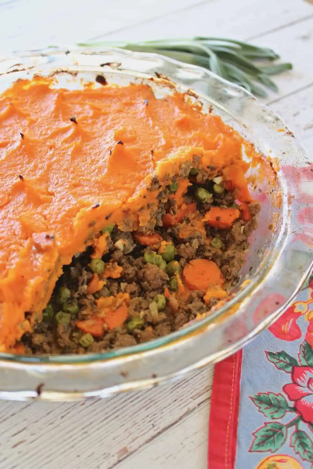 Close up of sweet potato shepherd's pie in a clear pie dish with pieces taken out of it