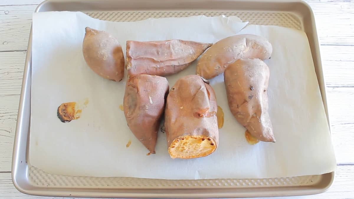 Cooked sweet potatoes with the skin on on a baking sheet