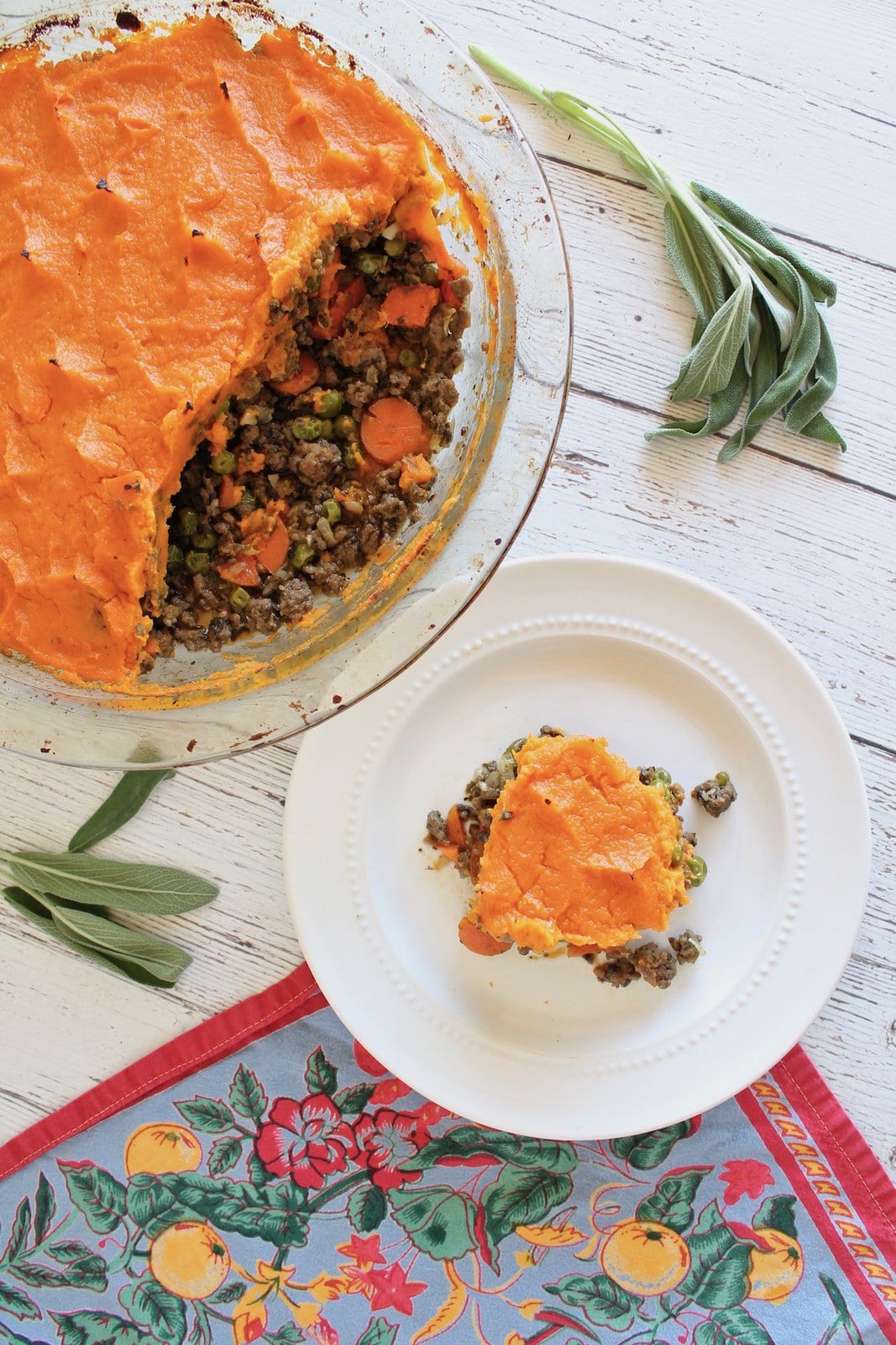 overhead view of sweet potato shepherd's pie with pieces taken out of it and a slice on a separate white plate