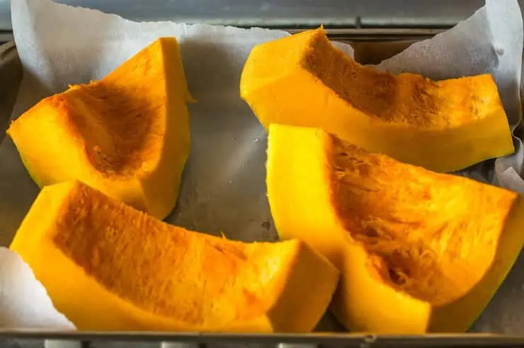 Large chunks of pumpkin on a baking sheet lined with parchment paper