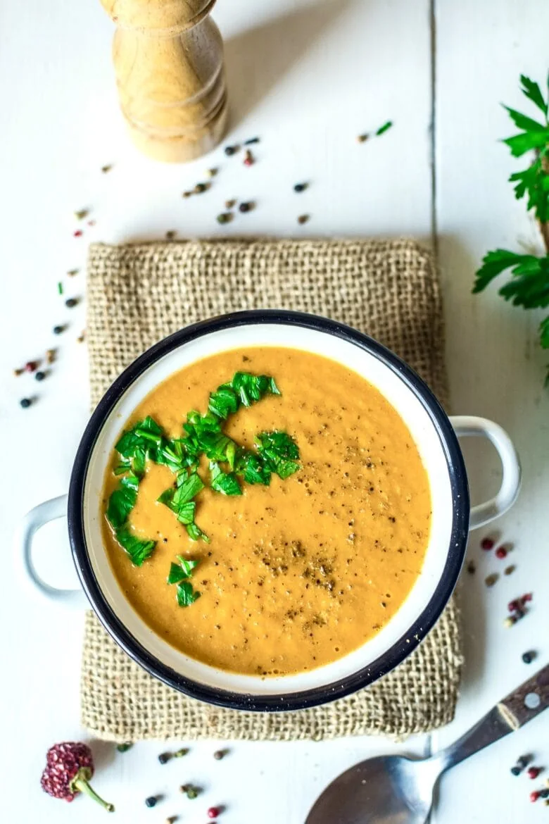 A bowl of creamy roasted vegetable soup with a spoon.