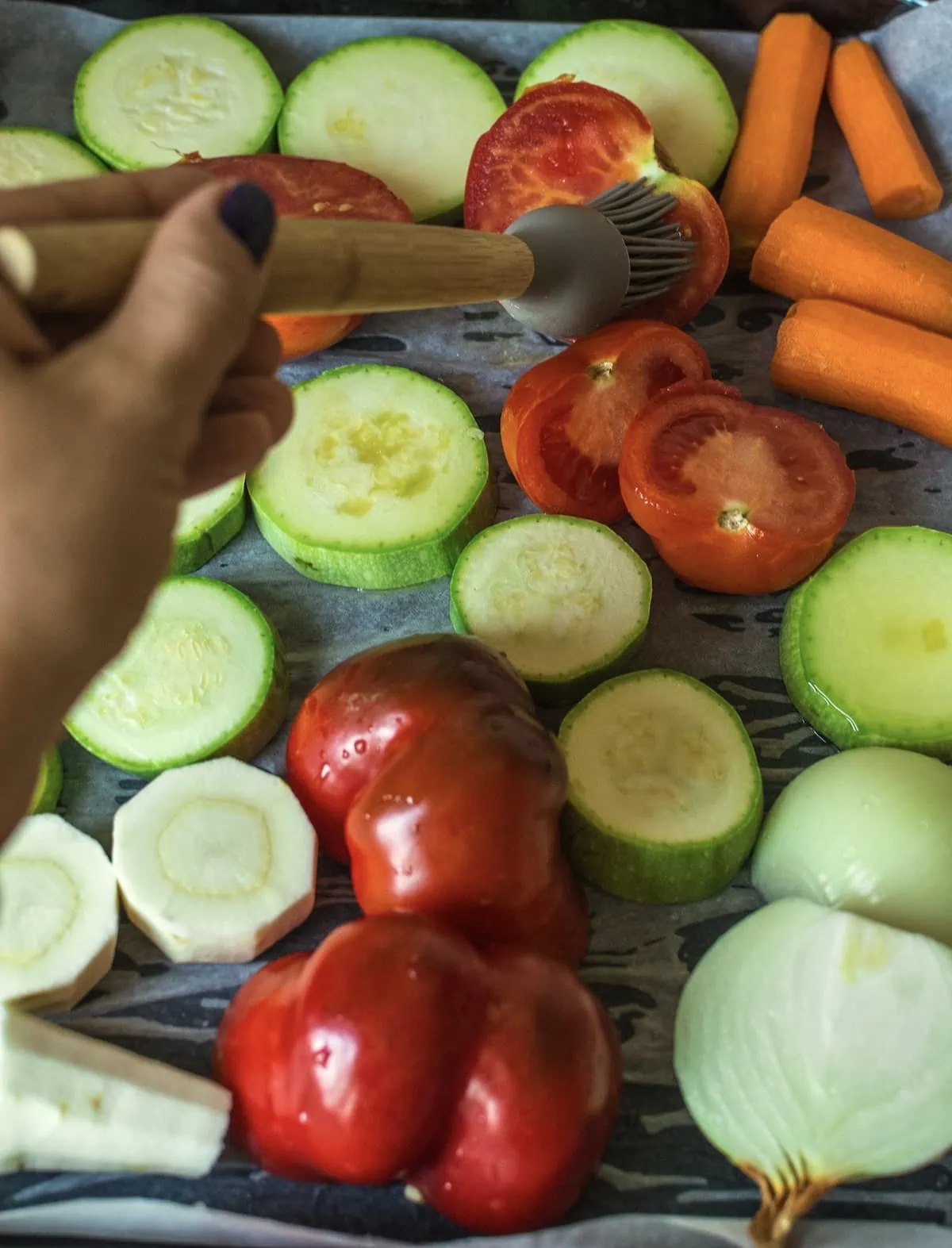 A person is preparing vegetables by brushing oil on them.